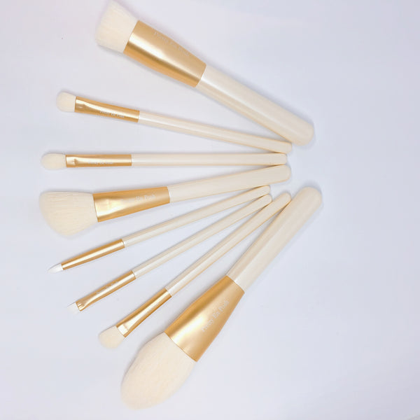 Makeup brush set with white bristles and gold accents.