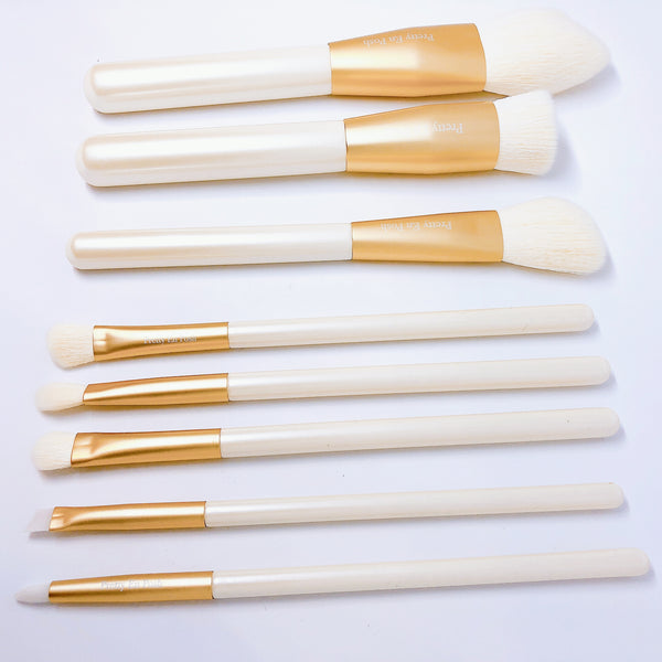 Makeup brush set with white bristles and gold accents.