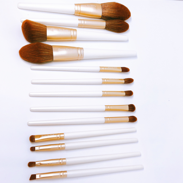 Makeup brush set with brown bristles, gold accents and white handle.