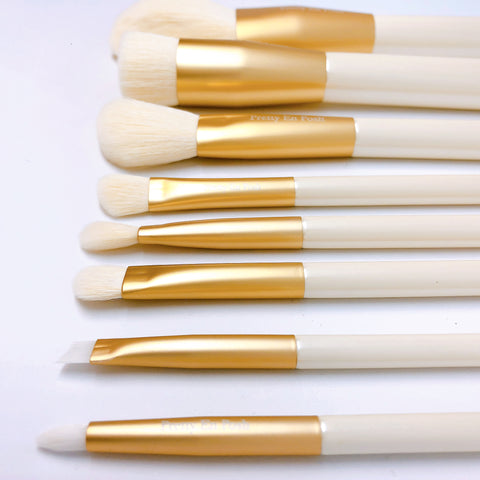 Makeup brush set with white bristles and gold accents.