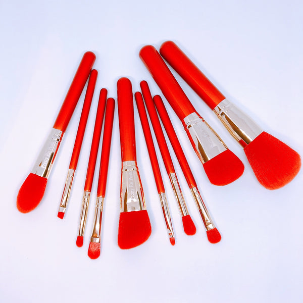 Makeup brush set with red bristols and handle.