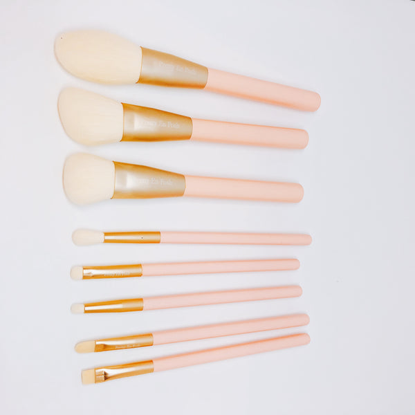 Makeup brush set with white bristles, gold accents and pink handle.